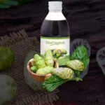 noni bebida botánico, presentado en una botella de vidrio, fruta de noni con hojas de noni.