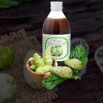 noni bebida botánico, presentado en una botella de vidrio, fruta de noni con hojas de noni.